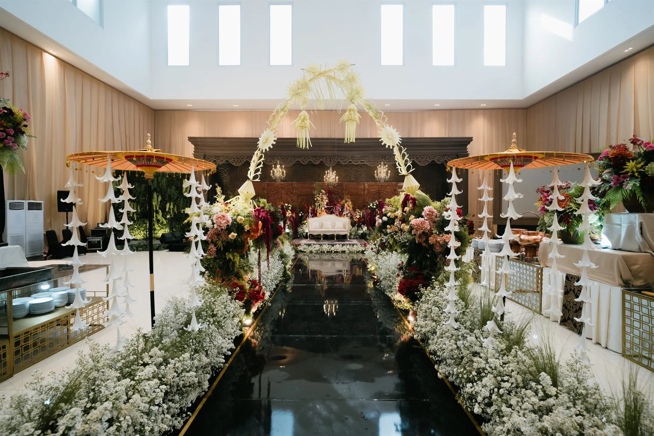 Lorong masuk resepsi dengan payung emas dan rangkaian bunga putih di Aula At-Taqwa Sriwijaya